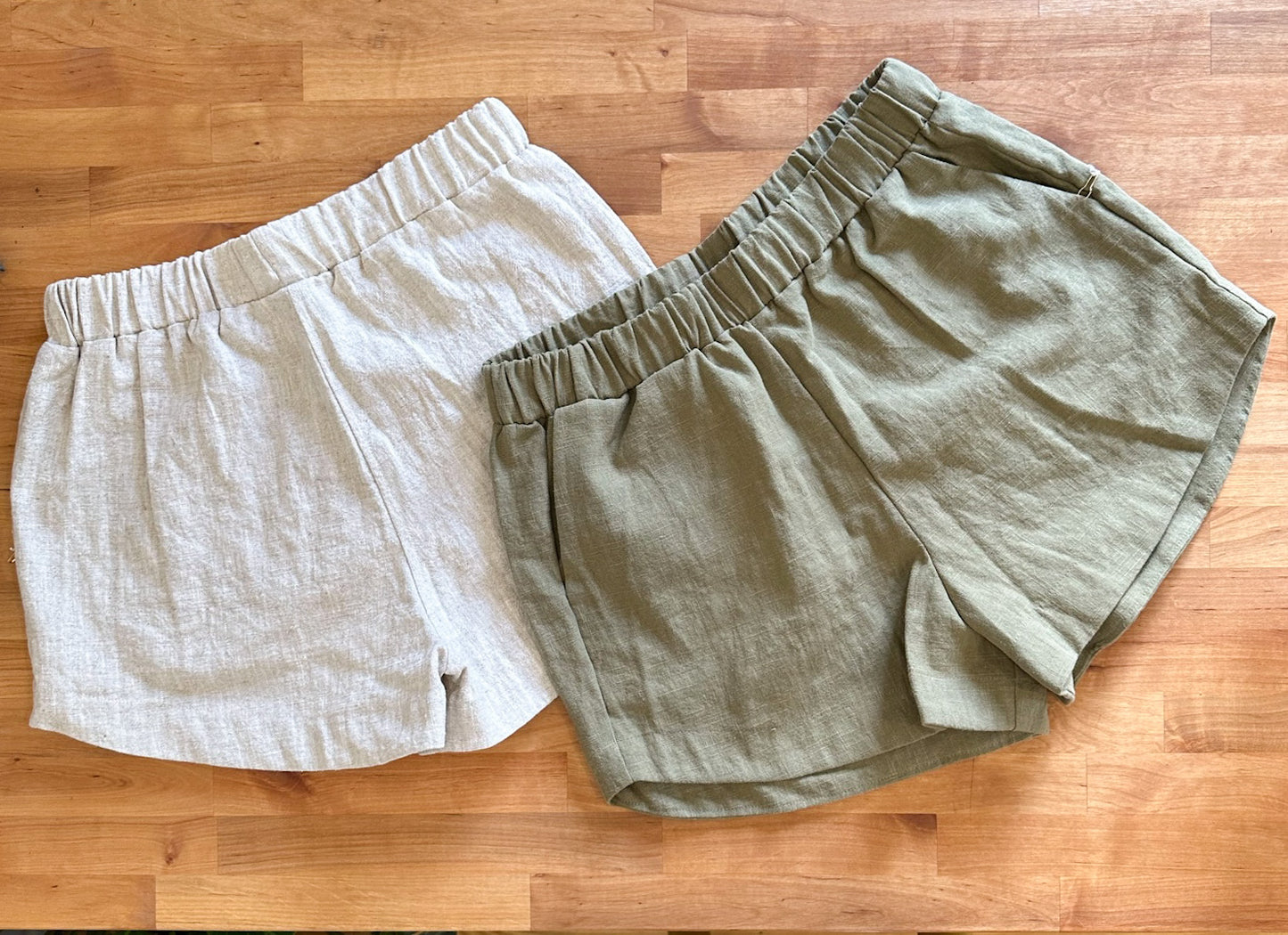 Flat lay of kepola design house Delphi linen shorts in oyster and artichoke