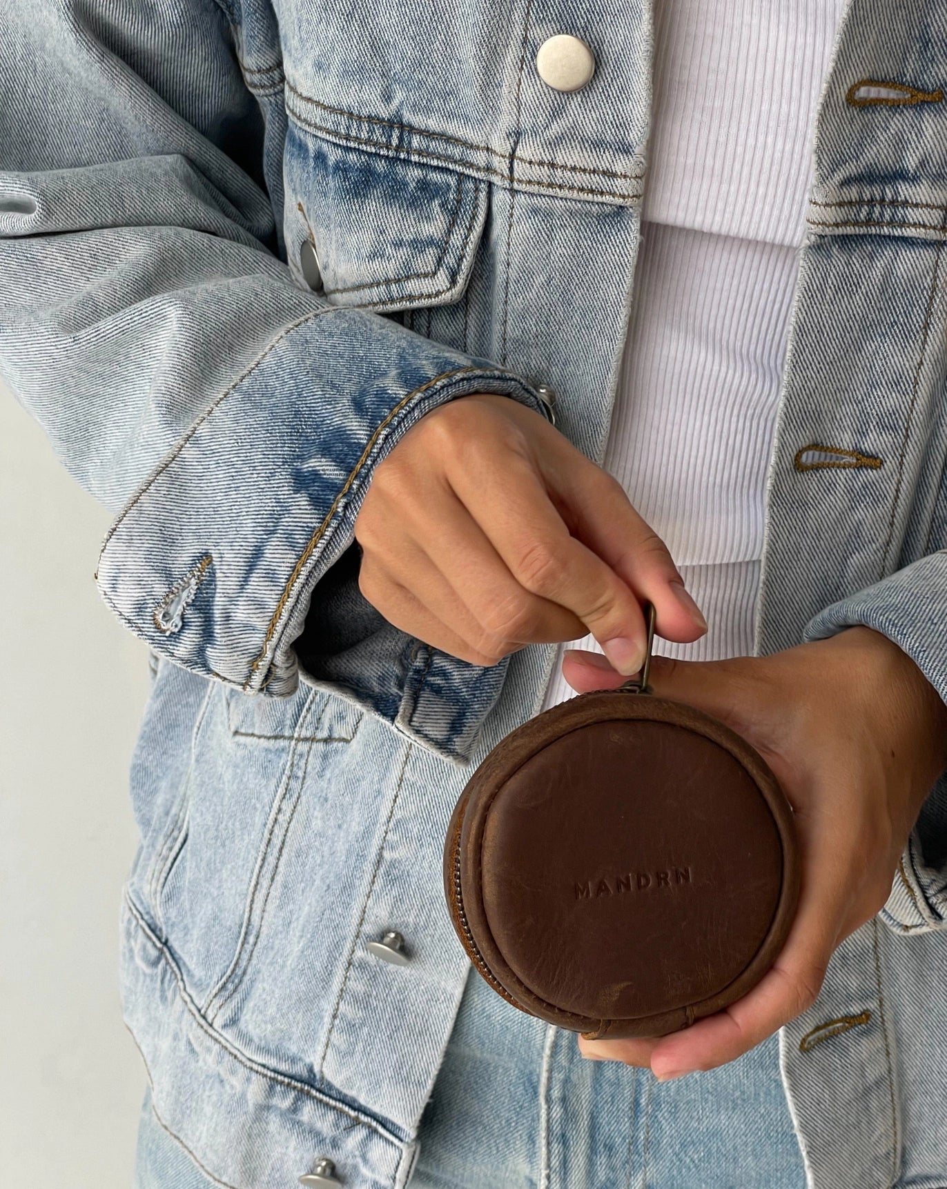 Person holding leather mandrn rover circle pouch in color saddle
